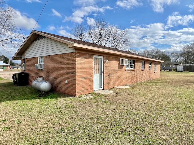 rear view of property featuring a yard, brick siding, and cooling unit