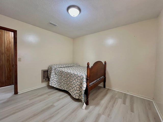 bedroom with visible vents, light wood-style flooring, and baseboards