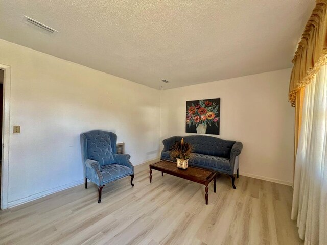 living area with visible vents, a textured ceiling, and light wood-style flooring