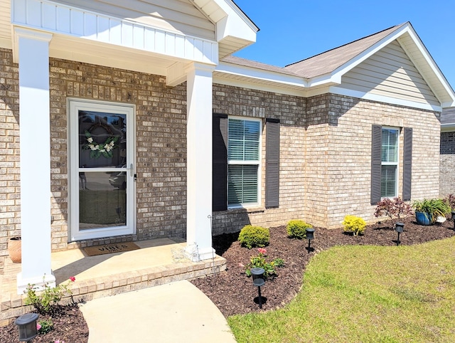 doorway to property with brick siding and a porch