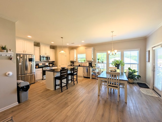 dining space with light wood-type flooring, ornamental molding, an inviting chandelier, and recessed lighting