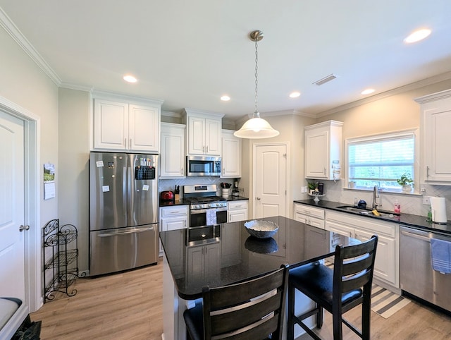 kitchen featuring light wood-style floors, appliances with stainless steel finishes, dark countertops, a sink, and visible vents