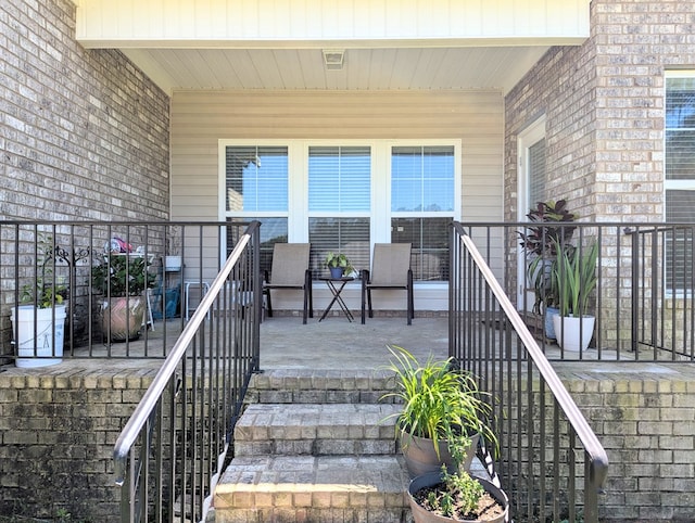view of exterior entry featuring brick siding and a porch