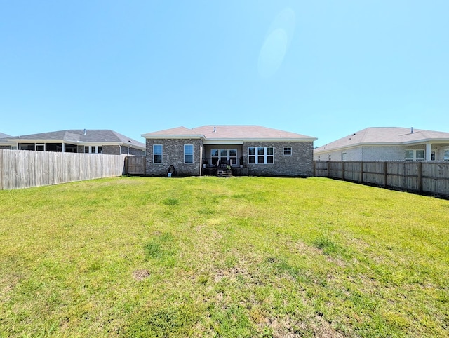 rear view of property with a fenced backyard and a lawn