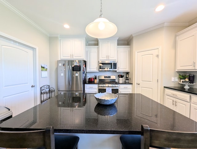 kitchen featuring ornamental molding, a kitchen breakfast bar, white cabinets, and stainless steel appliances
