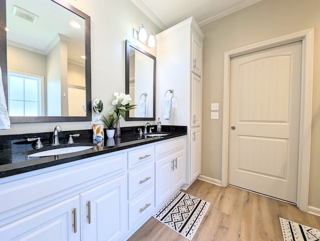 full bathroom featuring visible vents, wood finished floors, crown molding, and a sink