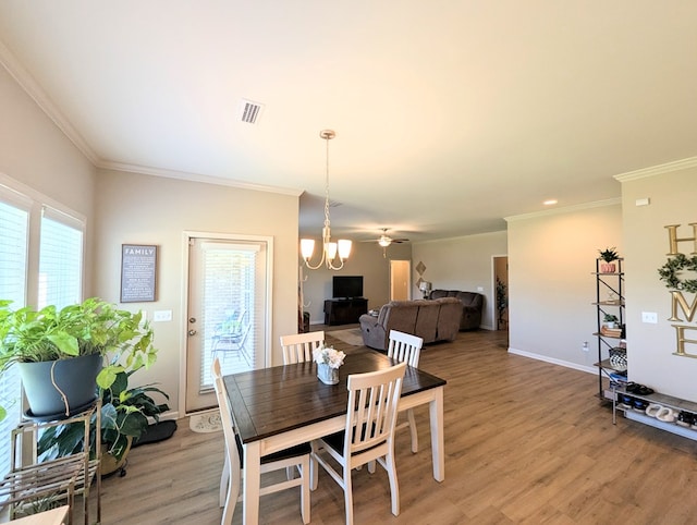 dining room with ornamental molding, light wood finished floors, an inviting chandelier, and a wealth of natural light