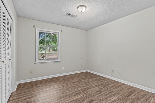 unfurnished bedroom featuring a closet, dark wood-type flooring, and a textured ceiling