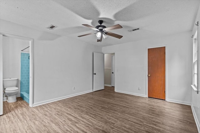 unfurnished bedroom with hardwood / wood-style floors, ceiling fan, a textured ceiling, and ensuite bath