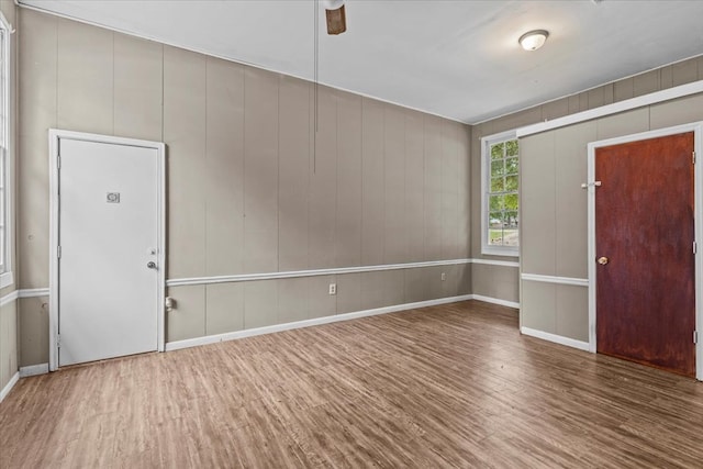 foyer with ceiling fan, wood walls, and wood-type flooring