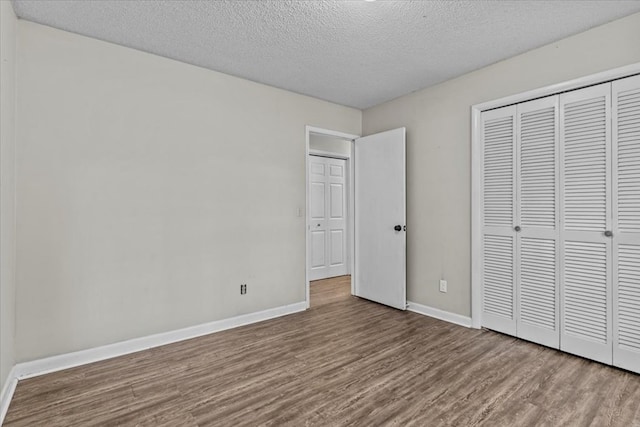 unfurnished bedroom with a closet, wood-type flooring, and a textured ceiling