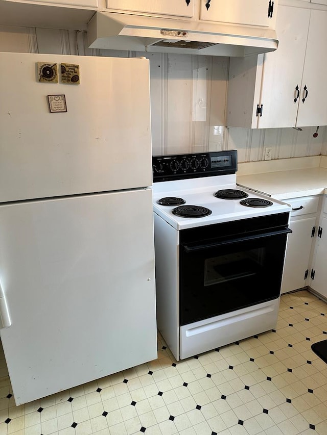 kitchen with electric range, freestanding refrigerator, light countertops, white cabinetry, and light flooring
