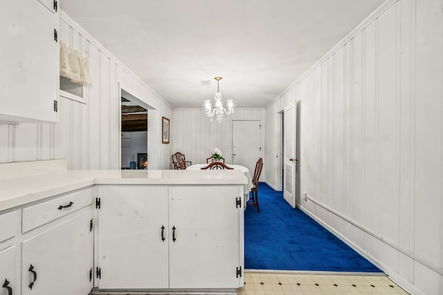 702 Highland St, Dothan, AL 36301 - kitchen featuring white cabinetry, a chandelier, dark colored carpet, a peninsula, and crown molding