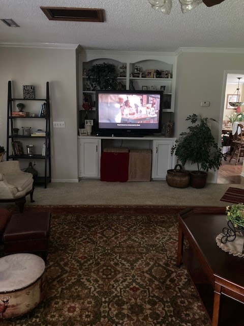 living room with a textured ceiling, ornamental molding, visible vents, and light colored carpet