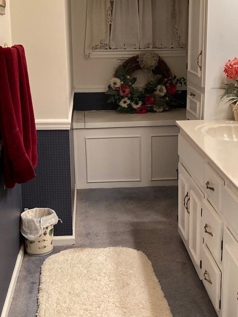 bathroom featuring a wainscoted wall, a decorative wall, and vanity