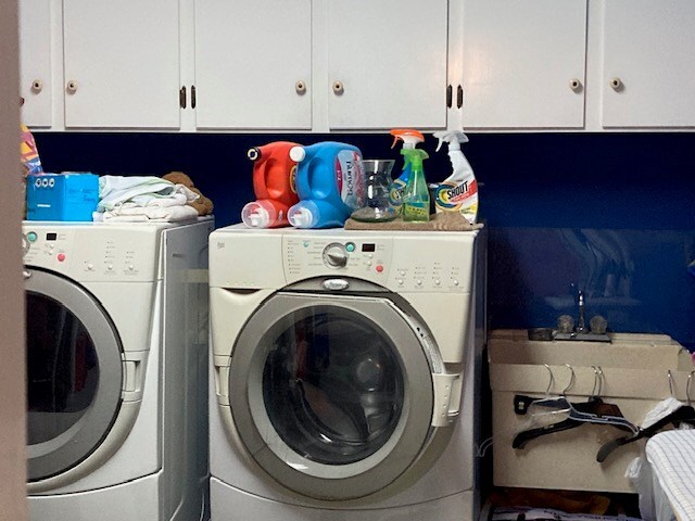 clothes washing area featuring cabinets and washing machine and dryer