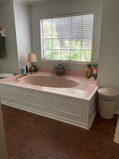 bathroom featuring a healthy amount of sunlight, ornamental molding, and a tub to relax in