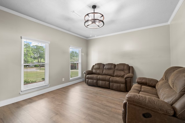 living area featuring a chandelier, baseboards, light wood-style floors, and ornamental molding