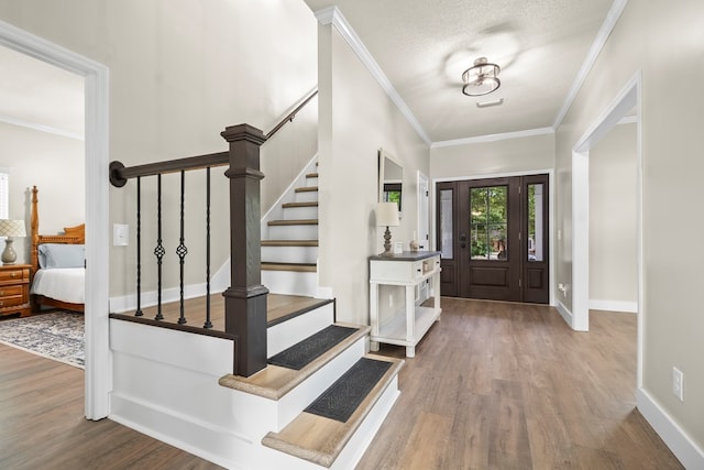 entryway featuring stairway, wood finished floors, visible vents, and ornamental molding