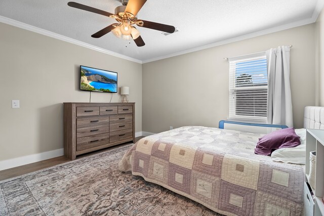 bedroom featuring a ceiling fan, baseboards, crown molding, and wood finished floors