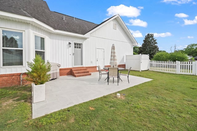 rear view of property featuring a lawn, a shingled roof, fence, a patio, and entry steps