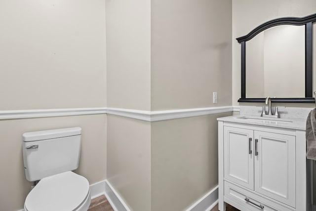 bathroom with baseboards, vanity, and toilet