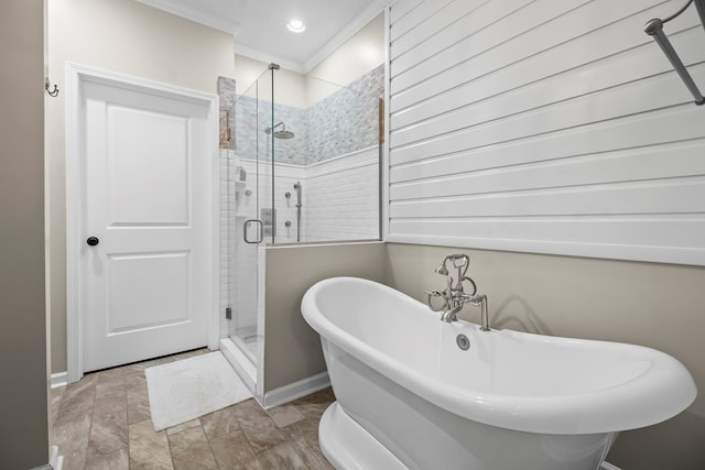 full bath with baseboards, crown molding, a freestanding tub, and a stall shower