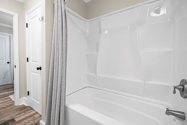 full bathroom featuring ornamental molding, wood finished floors, and shower / bathtub combination with curtain