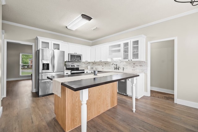 kitchen featuring stainless steel appliances, dark wood-type flooring, a center island, decorative backsplash, and white cabinetry