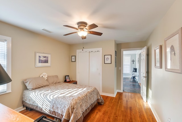 bedroom with multiple windows, wood-type flooring, and ceiling fan