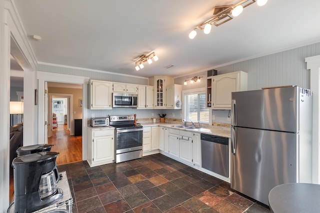 kitchen featuring white cabinets, appliances with stainless steel finishes, crown molding, and sink