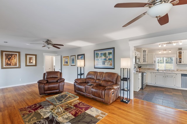 living room with wood-type flooring, ceiling fan, and sink