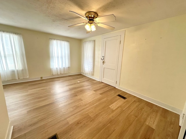 interior space featuring light wood finished floors, visible vents, ceiling fan, and baseboards