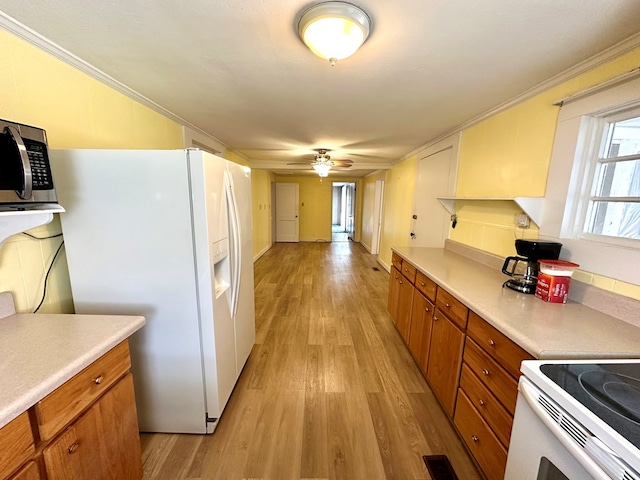 kitchen with visible vents, stainless steel microwave, white refrigerator with ice dispenser, brown cabinetry, and light countertops