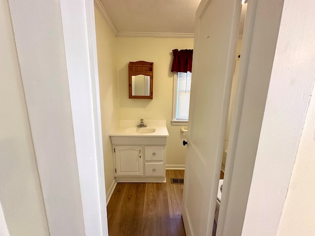 bathroom with visible vents, crown molding, baseboards, wood finished floors, and vanity