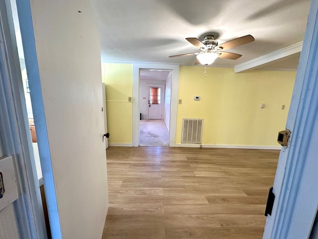 spare room with visible vents, light wood-style flooring, crown molding, baseboards, and ceiling fan