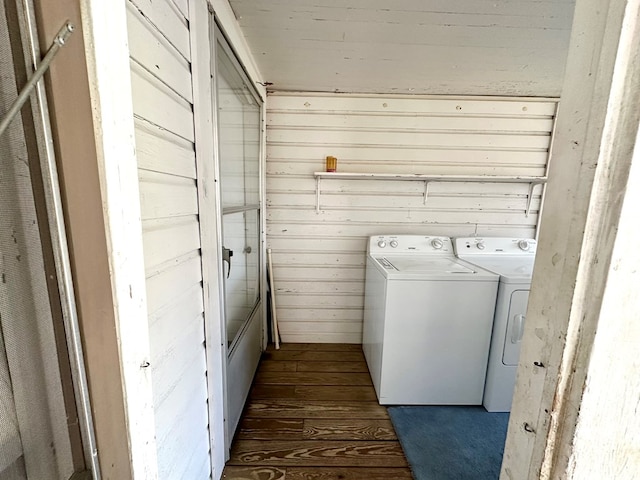 clothes washing area with washer and dryer, wooden walls, dark wood finished floors, and laundry area