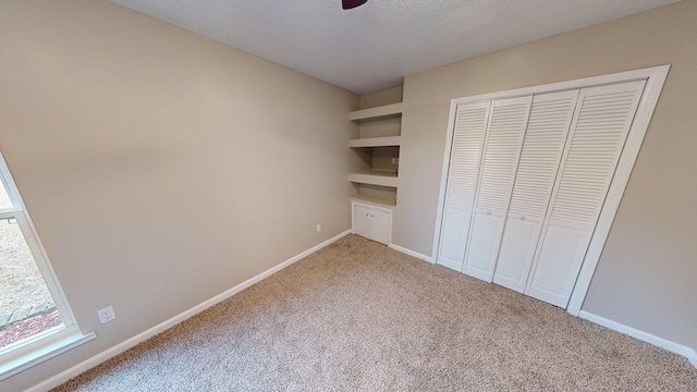 unfurnished bedroom with light carpet, a textured ceiling, a closet, and ceiling fan