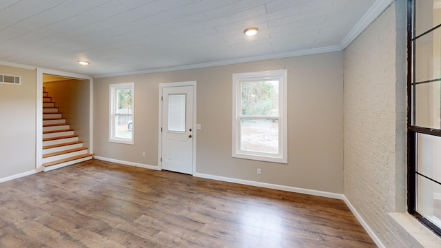 interior space with hardwood / wood-style floors, ornamental molding, a healthy amount of sunlight, and brick wall