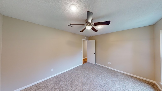 carpeted empty room featuring ceiling fan and a textured ceiling