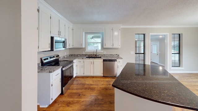 kitchen with dark stone counters, white cabinets, sink, a textured ceiling, and stainless steel appliances