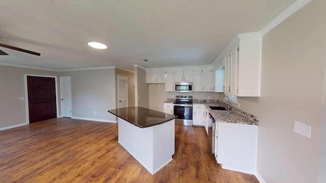 kitchen with dark stone counters, sink, appliances with stainless steel finishes, a kitchen island, and white cabinetry