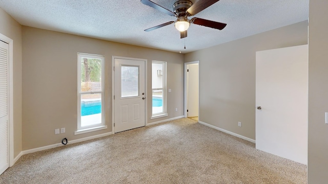 carpeted spare room with ceiling fan and a textured ceiling