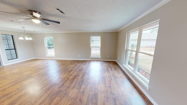 empty room with a healthy amount of sunlight, ornamental molding, and a textured ceiling