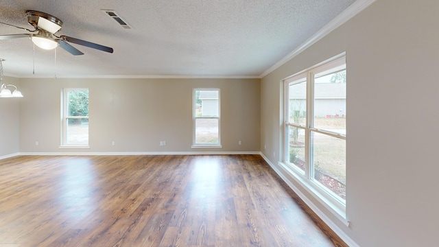 spare room featuring wood-type flooring, a textured ceiling, a wealth of natural light, and ornamental molding