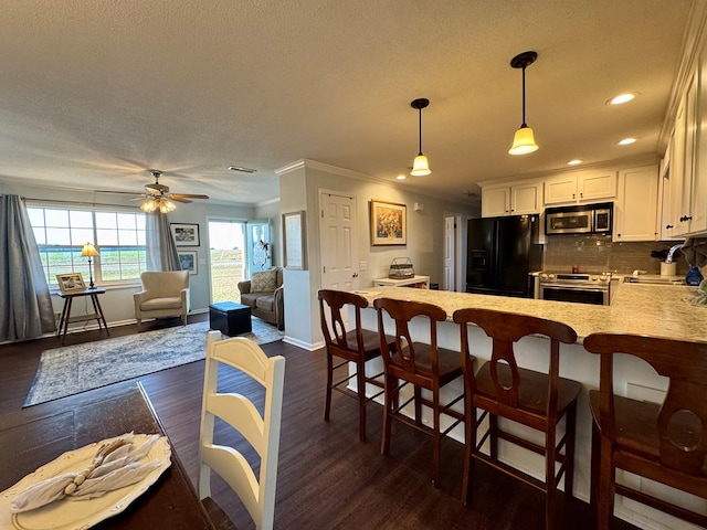 kitchen with crown molding, sink, dark hardwood / wood-style floors, appliances with stainless steel finishes, and kitchen peninsula