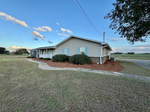 view of side of property with central AC unit, covered porch, and a yard