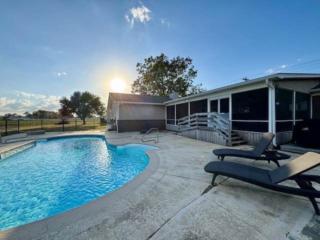 view of swimming pool with a sunroom and a patio