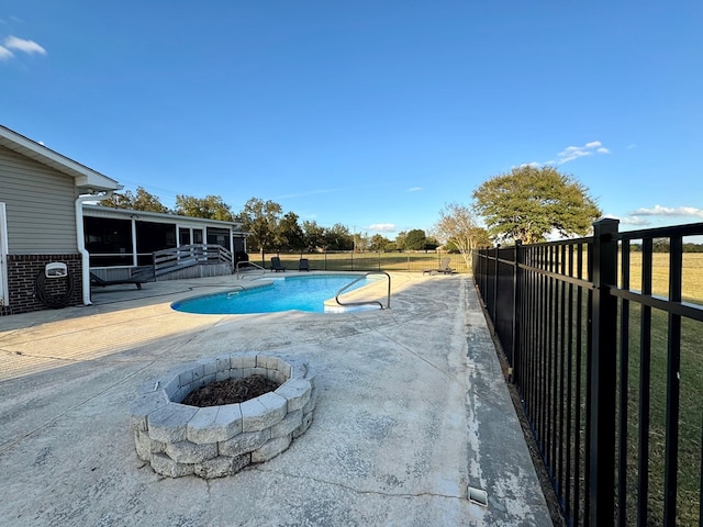 view of pool with a patio area, a sunroom, and a fire pit