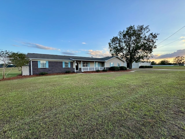 ranch-style house with a lawn and covered porch